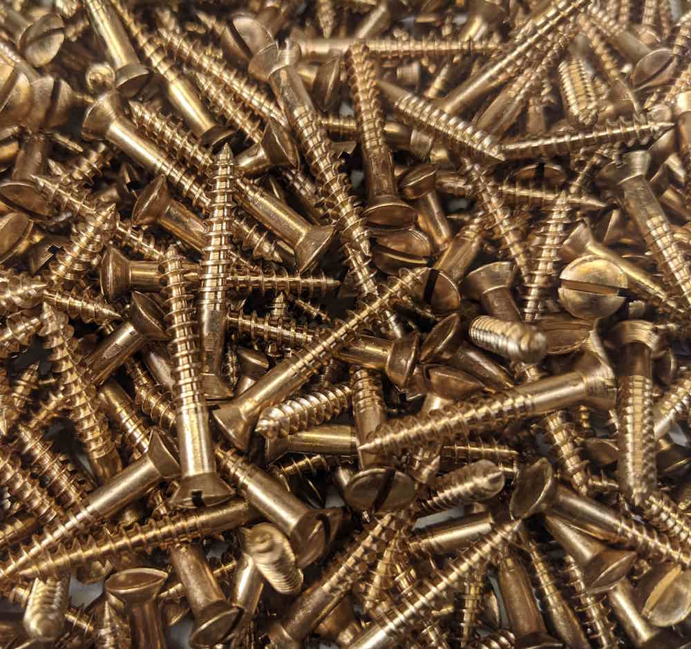 A pile of oval head, countersunk, slotted drive bronze wood screws